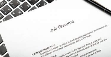 Resume and black pen on laptop in a home office