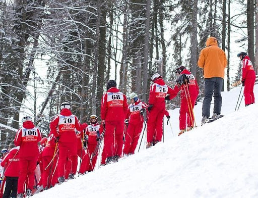 ski instructors waiting on side of ski hill in red uniforms