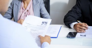 applicant holding resume in hands while being interviewed by employers