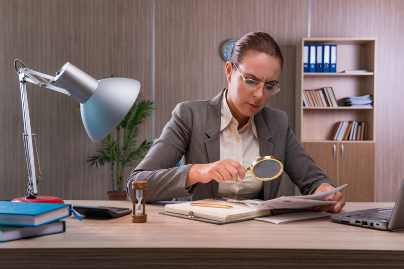 female forensic accountant studying documents with a magnifying glass