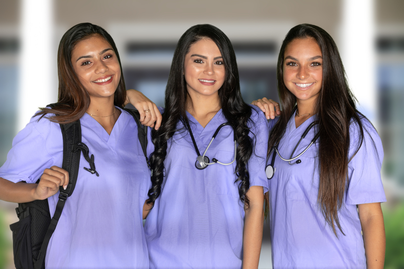 three young smiling female nurses wearing purple scrubs